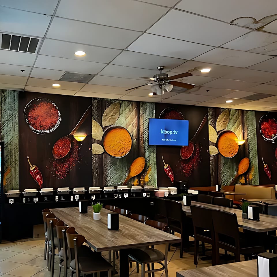 Interior of Chameli Restaurant with a spice-themed mural, buffet line, and dining tables.