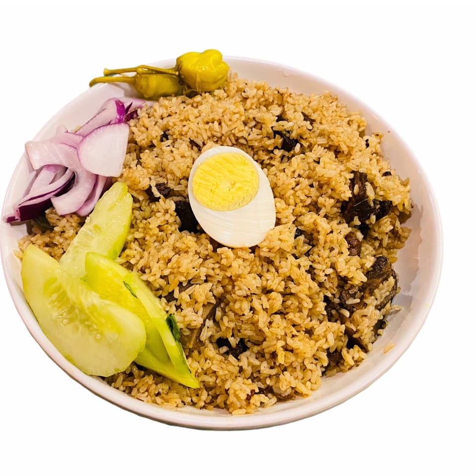 A bowl of Bangladeshi beef biryani with a hard-boiled egg, sliced cucumbers, red onions, and pickled peppers.