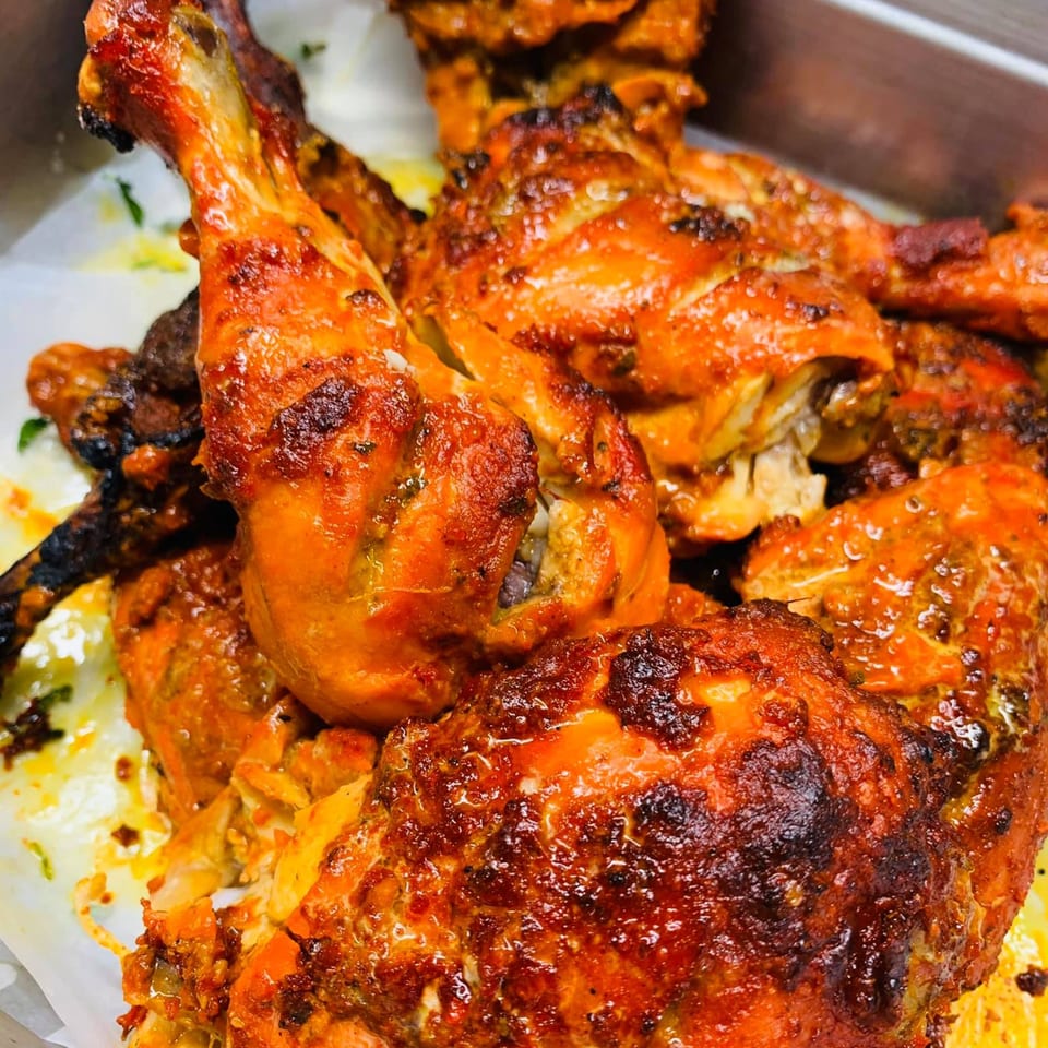 Close-up of several pieces of golden-brown roasted chicken with crispy skin, likely Chameli Restaurant's Bangladeshi cuisine.