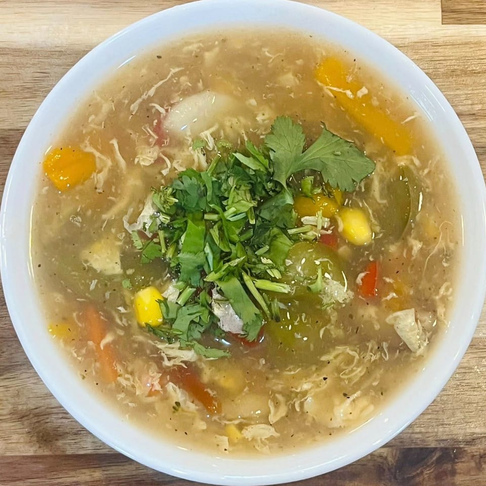A bowl of Chameli Restaurant's Bangladeshi chicken vegetable soup, garnished with fresh cilantro.