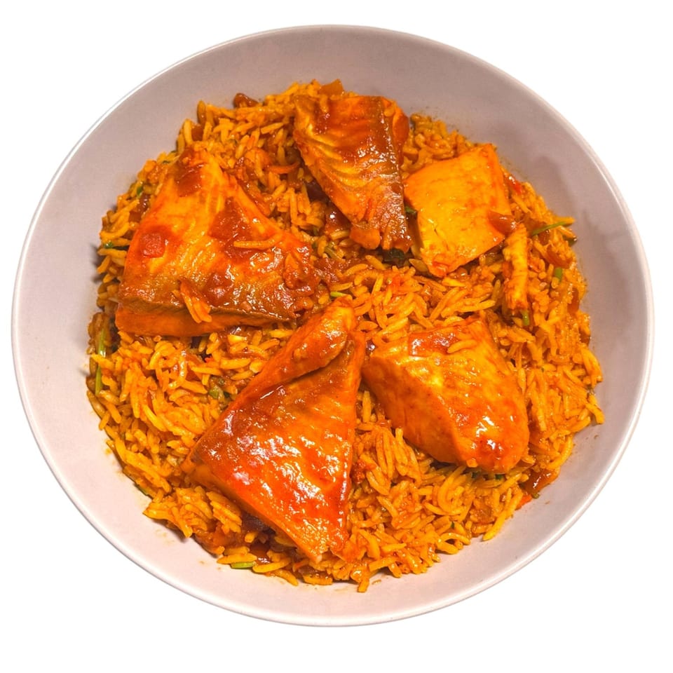 A bowl of Bangladeshi salmon biryani with vibrant orange rice and four pieces of salmon.