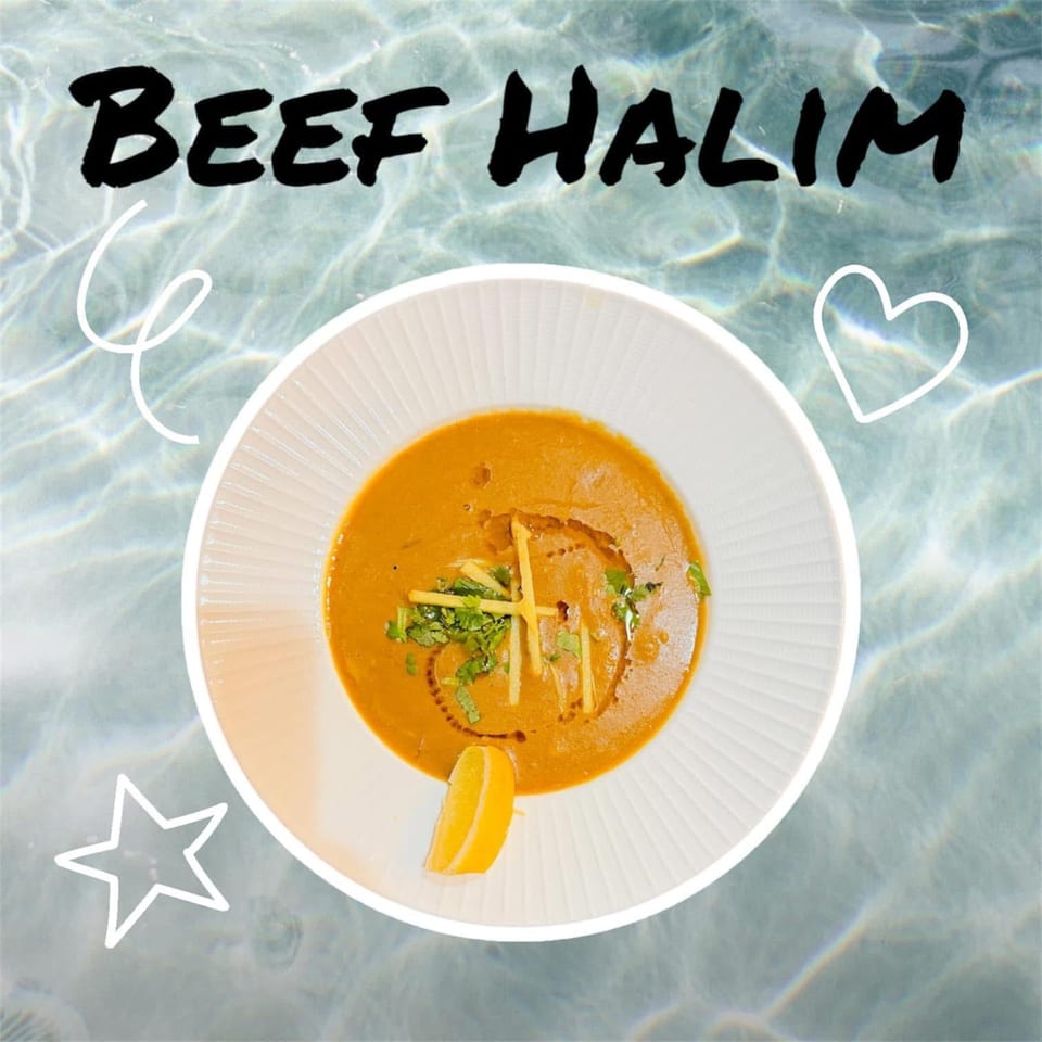 A bowl of Chameli Restaurant's Bangladeshi Beef Halim, garnished with ginger, cilantro, and a lemon wedge.