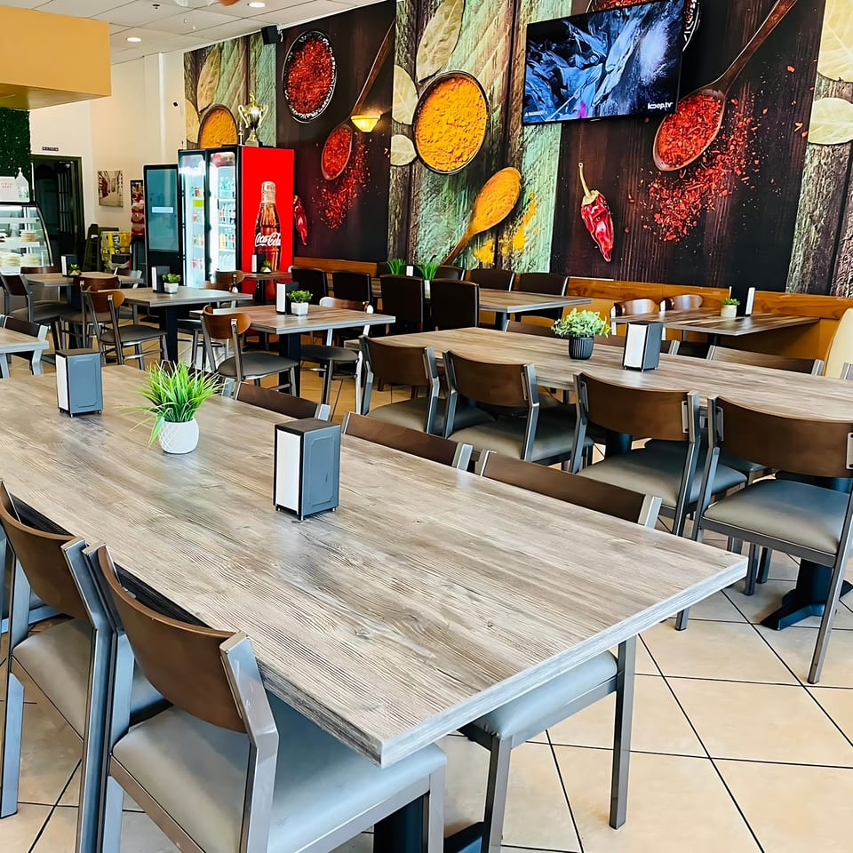 Interior of Chameli Restaurant with empty tables, chairs, and a spice-themed wall mural.