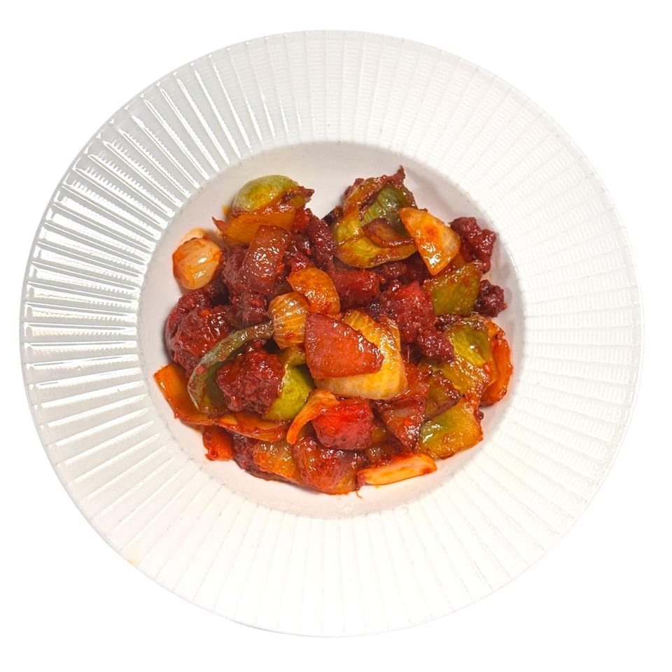 A white bowl filled with Chameli Restaurant's Bangladeshi stir-fried meat and colorful vegetables.